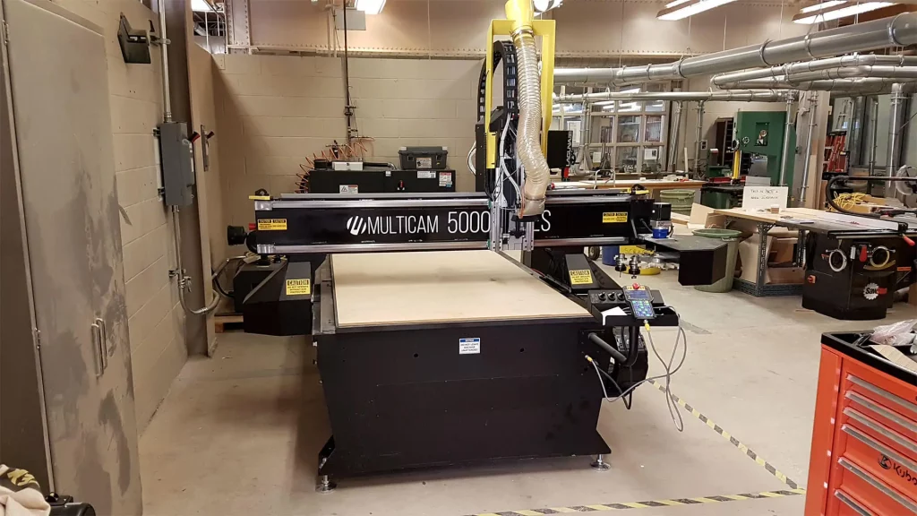 Close-up of the MultiCam 5000 Series CNC Router in operation at Toronto Metropolitan University’s Design + Technology LAB. The image showcases the machine’s spindle cutting through a sheet of aluminum with precision.