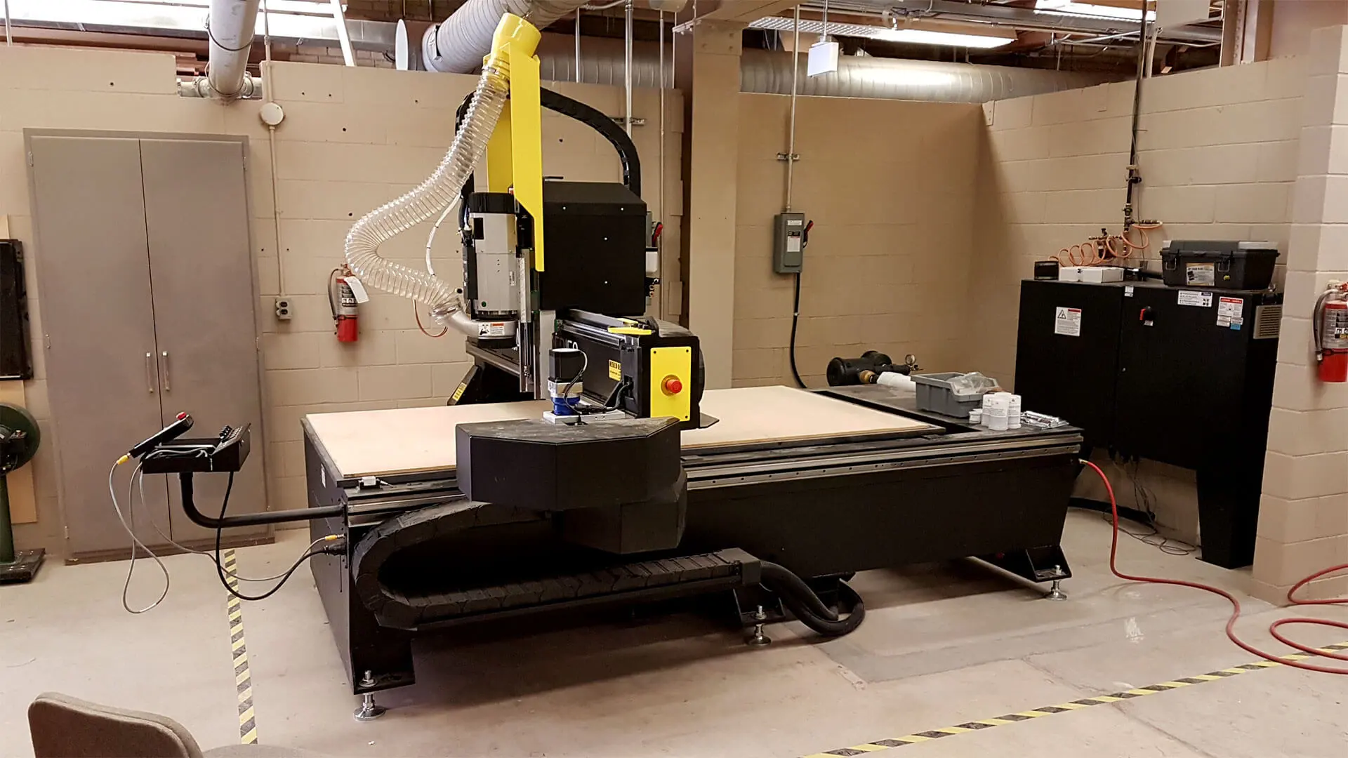 Side view of the MultiCam 5000 Series CNC Router installed in the university’s workshop. The machine's sturdy steel frame and gantry are visible, emphasizing its robust construction.